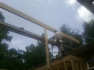 Carpenter setting a ridge beam over a new addition frame — Ice Dam Removal by Roofing Brothers in Willards