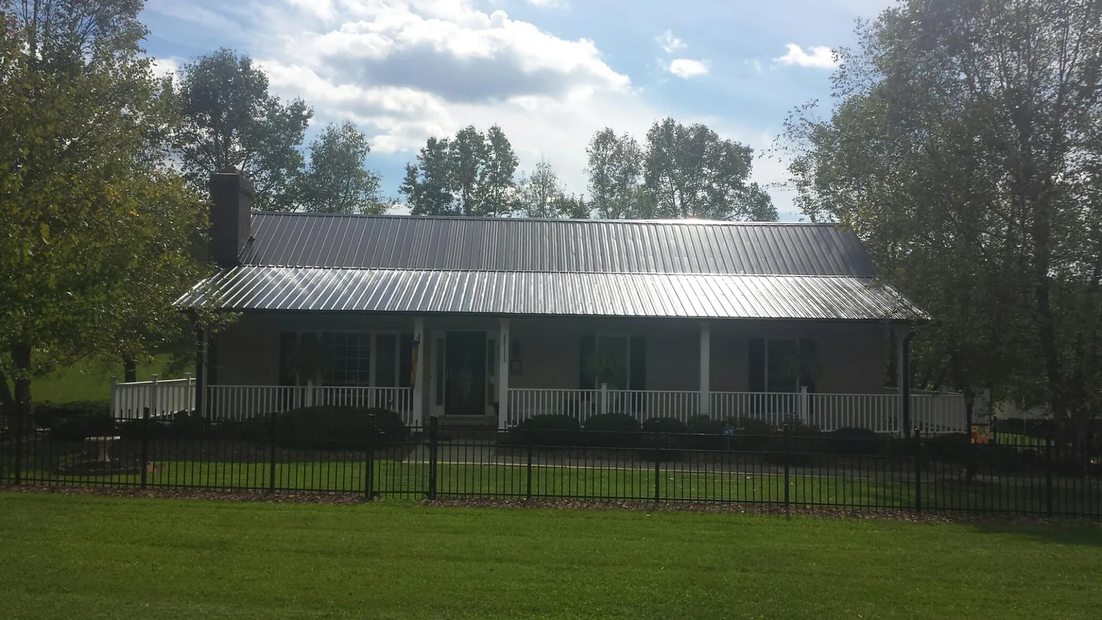 Gray metal roof on a brick ranch with a full width front porch — Gutter Guard Installation work by our crew in Willards